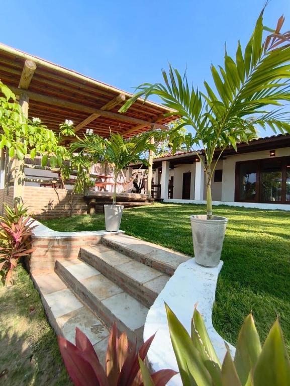 a garden with a wooden pathway with palm trees at Villa Tarifa Suites in Amontada