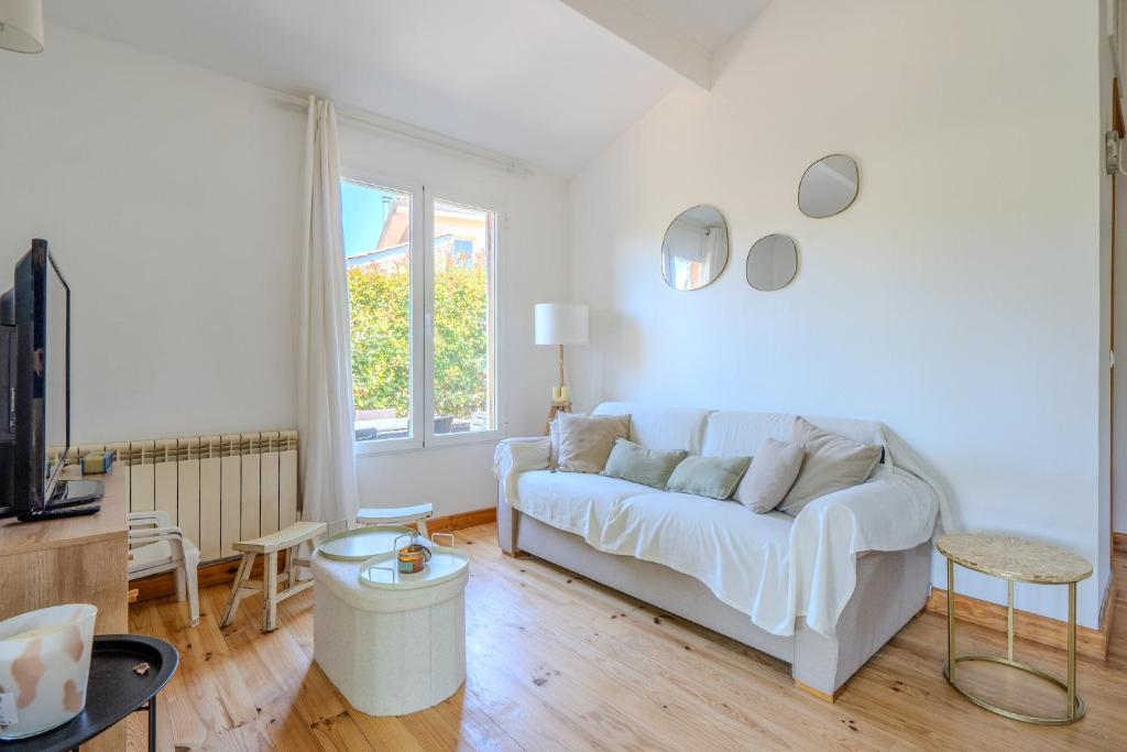 a living room with a white couch and a window at Chalet Cosy in Lège-Cap-Ferret