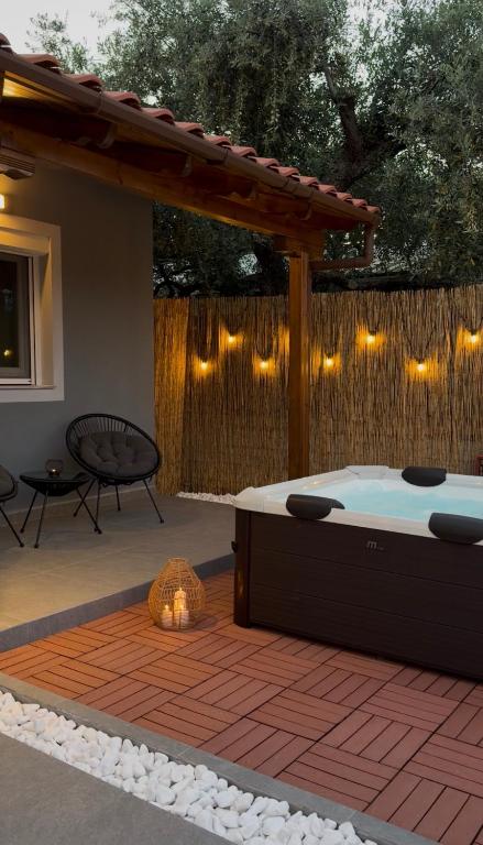 a hot tub on a patio with a fence with lights at Emerald Dream Oasis Studio in Skala Potamias
