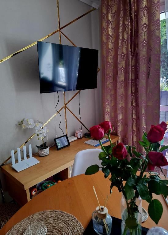 a desk with a television and a table with roses at Chillroom in Rąbień