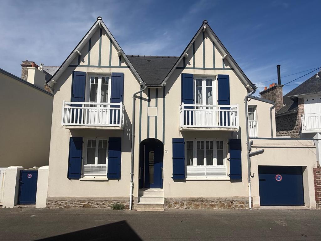 a large white house with blue shutters at GIte de la Grande Plage in Pléneuf-Val-André