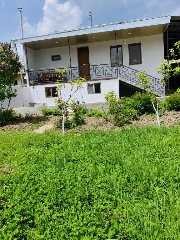 a white building with a balcony and some green grass at Syune House in Tatʼev