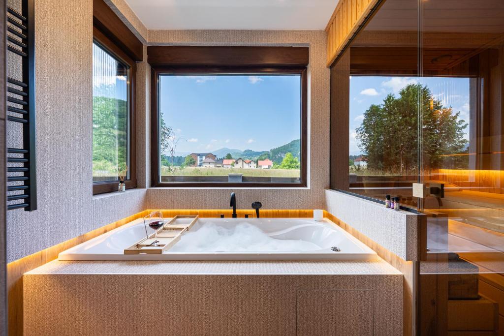 a large bath tub in a bathroom with a large window at MonteBreza Spa Apartment Jacuzzi, Sauna & Free Parking in Kolašin