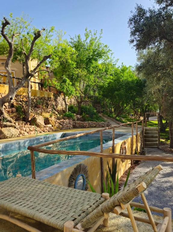 a resort with a swimming pool with a bench and trees at Dar Zaytoun Bhalil in Bhalil