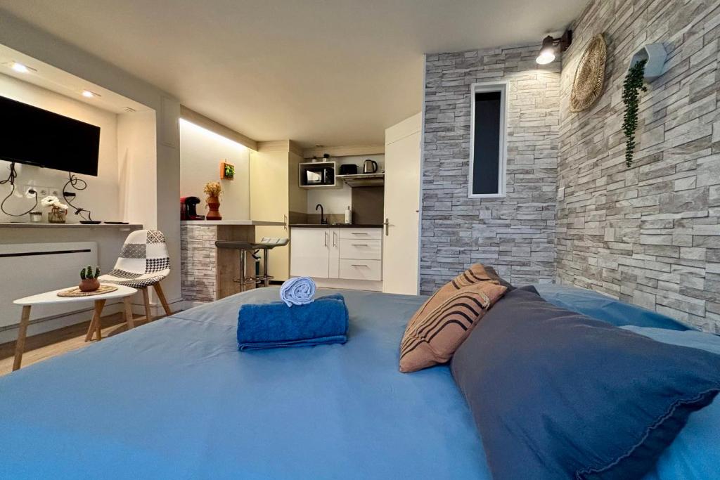 a large blue bed in a room with a brick wall at Etablissement Cloutiers comprenant plusieurs logements de type studio - Hyper Centre Brive in Brive-la-Gaillarde