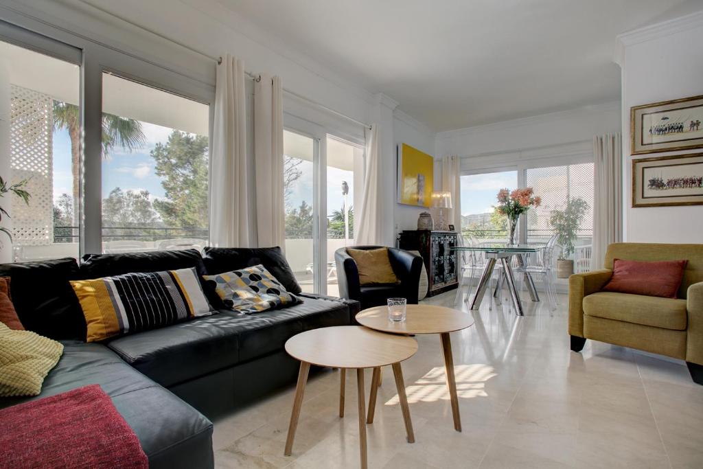 a living room with a black couch and a table at Sunny Golf Apartment in Estepona