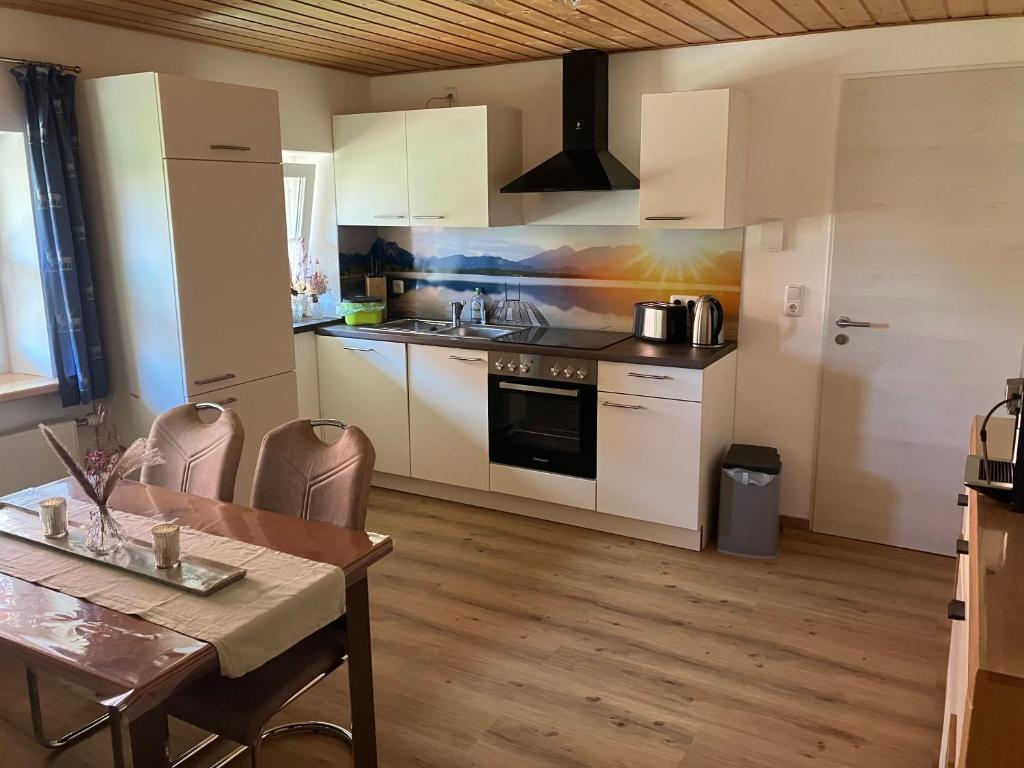 a kitchen with white cabinets and a table and a dining room at Ferienwohnung Eble bei Markt Rettenbach in Markt Rettenbach