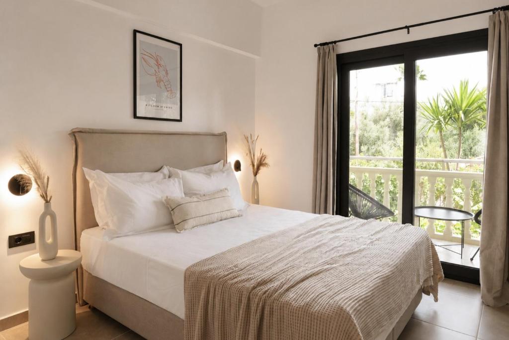 a white bedroom with a bed and a balcony at Abelia Boutique Rooms in Tsilivi