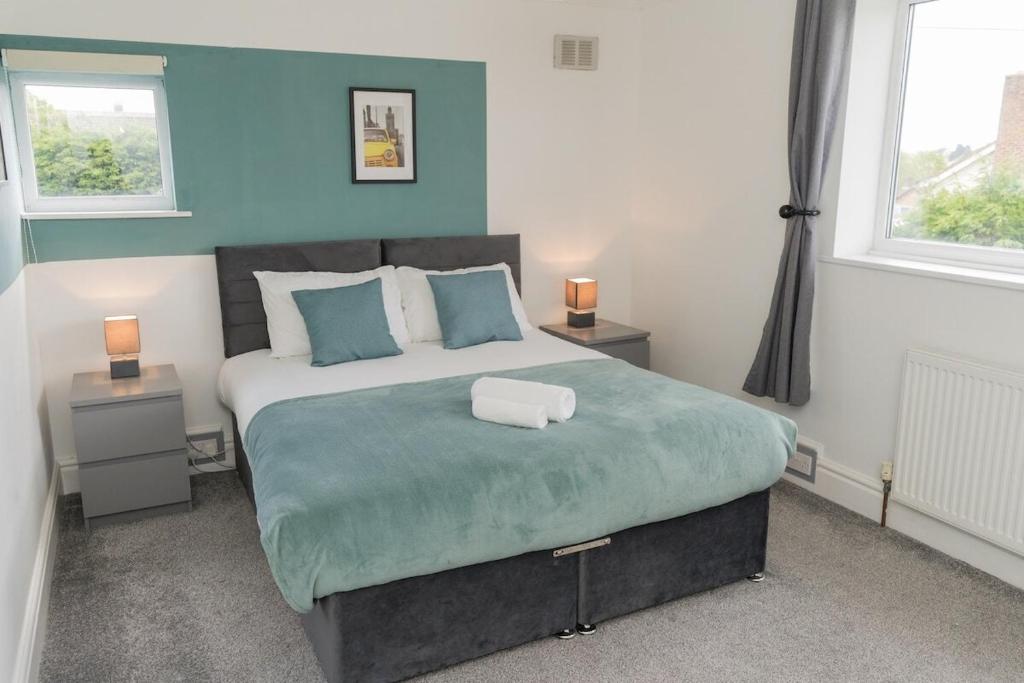 a bedroom with a large bed with blue walls and windows at Woodington House in Birmingham