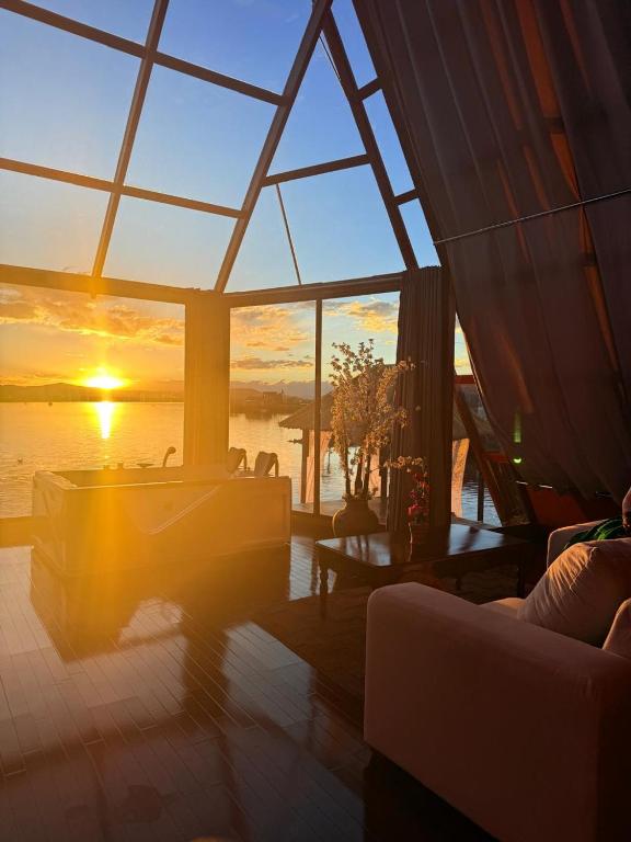 a living room with a view of the sunset at KAY PACHA LODGE Uros in Puno