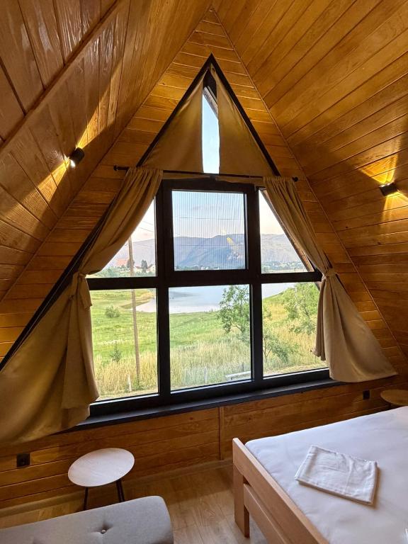 a bedroom with a large window in a wooden house at Country House Malekin in Ripci