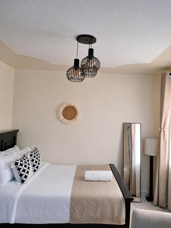 a bedroom with a bed and two chandeliers at Faymu Homes in Kitengela 