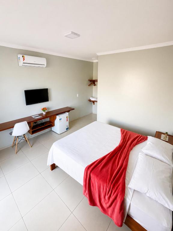 a bedroom with a white bed and a television at Bella Spiaggia Suítes Centro de Flecheiras, perto da praia in Flecheiras