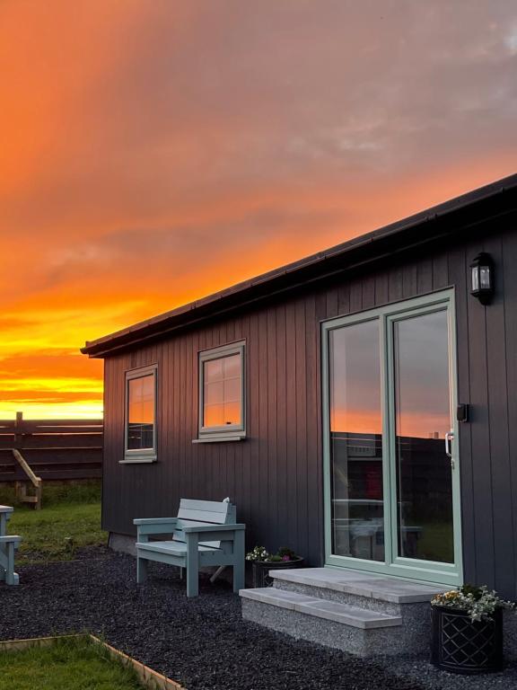 a small house with a bench and a sunset at The Glen Lodges, Muriel Cabin in Auckingill