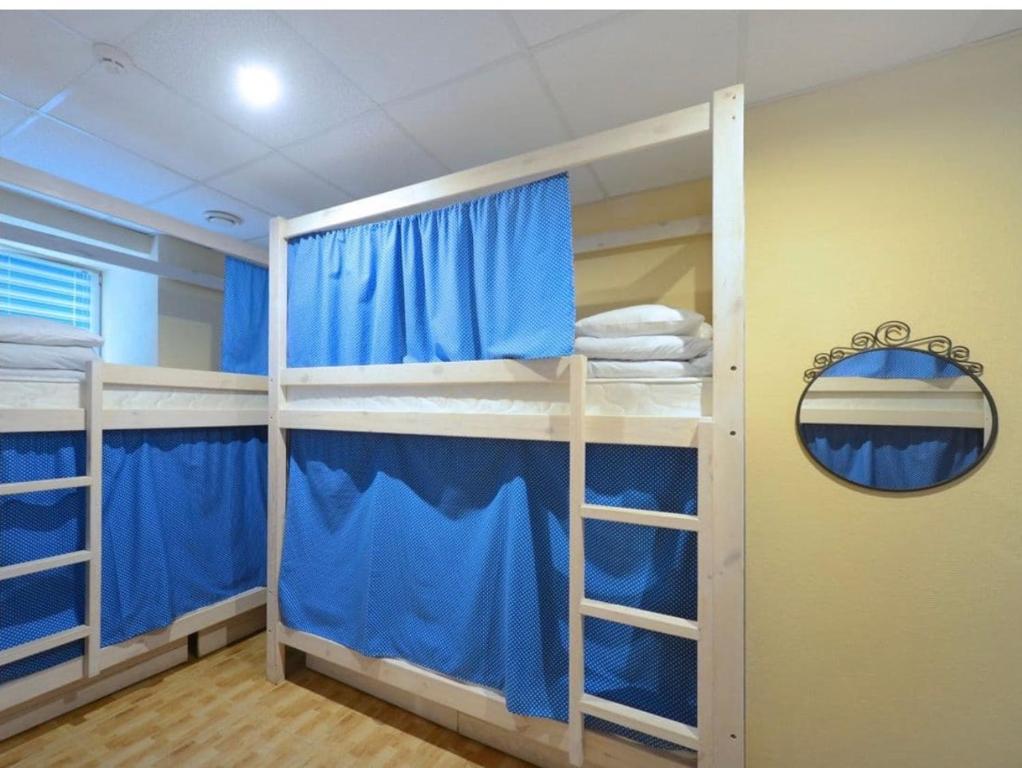 a room with three bunk beds with blue curtains at Good Dreams in Kyiv