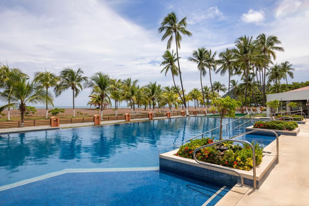 a large swimming pool with palm trees in the background at Best Western Jaco Beach All Inclusive Resort in Jacó