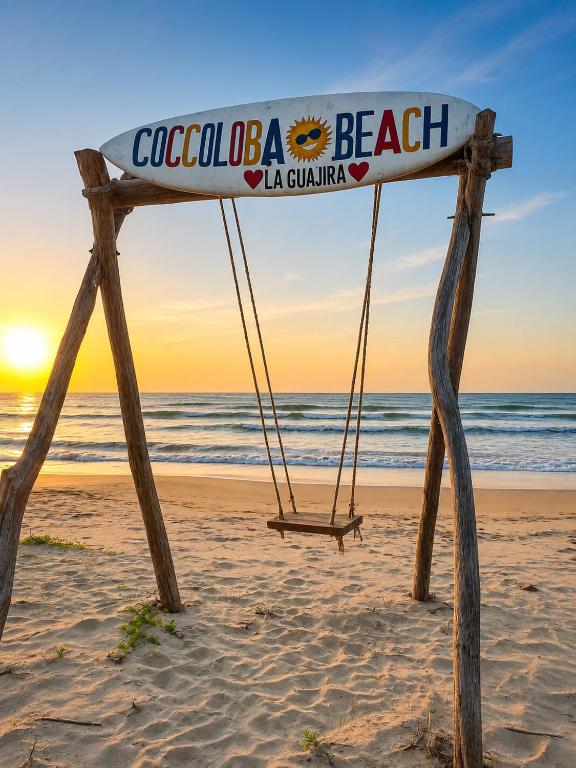 a sign on the beach with a swing at Coccoloba Beach Hotel in Dibulla