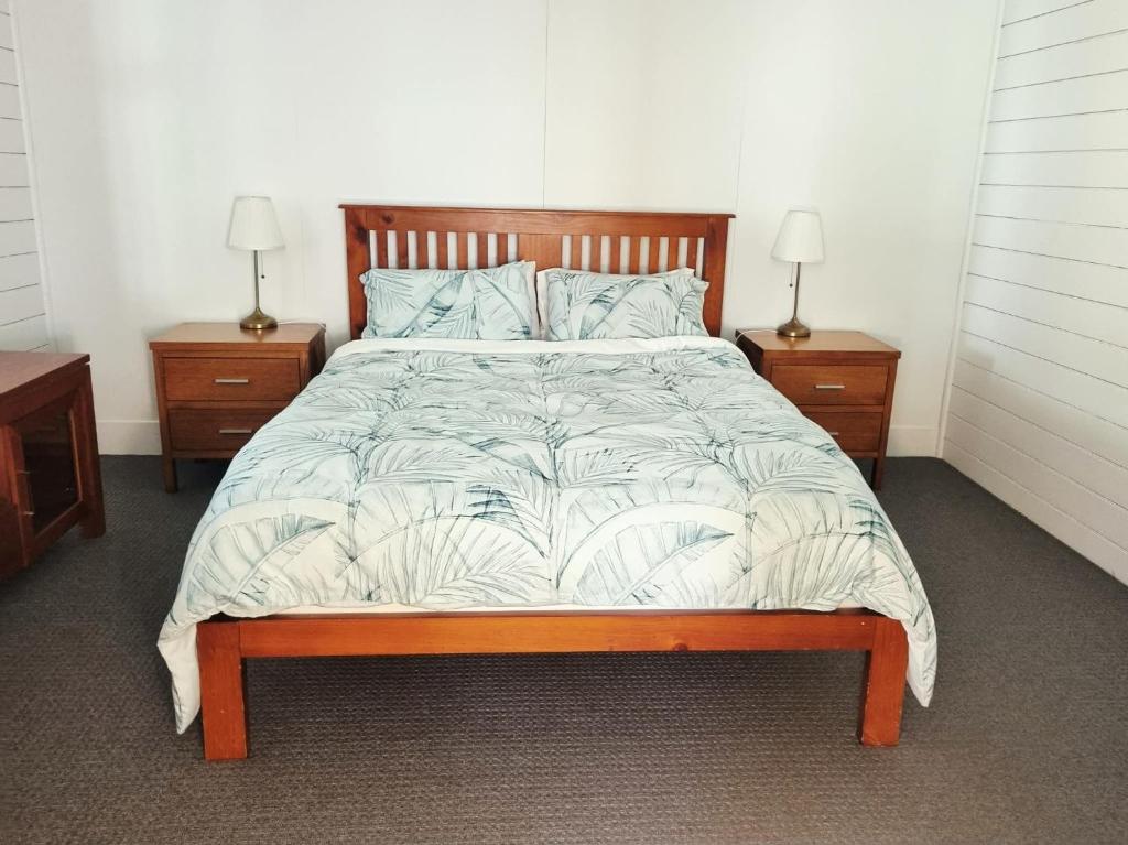 a bedroom with a bed with two nightstands and two lamps at Horseshoe House - Gympie in Gympie