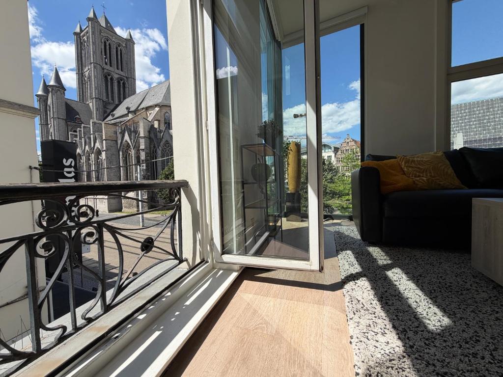 a balcony with a couch and a view of a church at Historic Centre Apartment - Ghent Belfry & St Nicholas Church View in Ghent