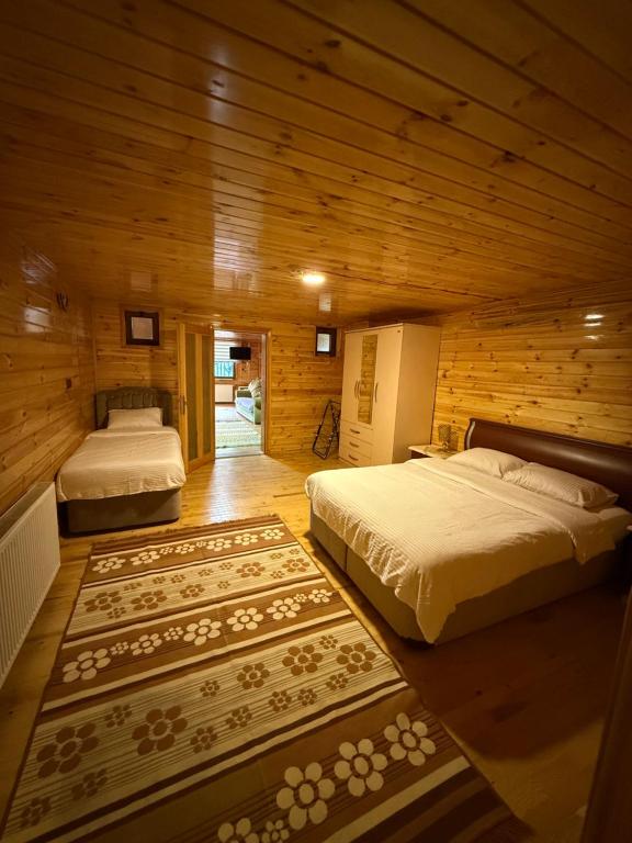 two beds in a room with wooden walls at Konçoğlu Pansiyon in Uzungöl