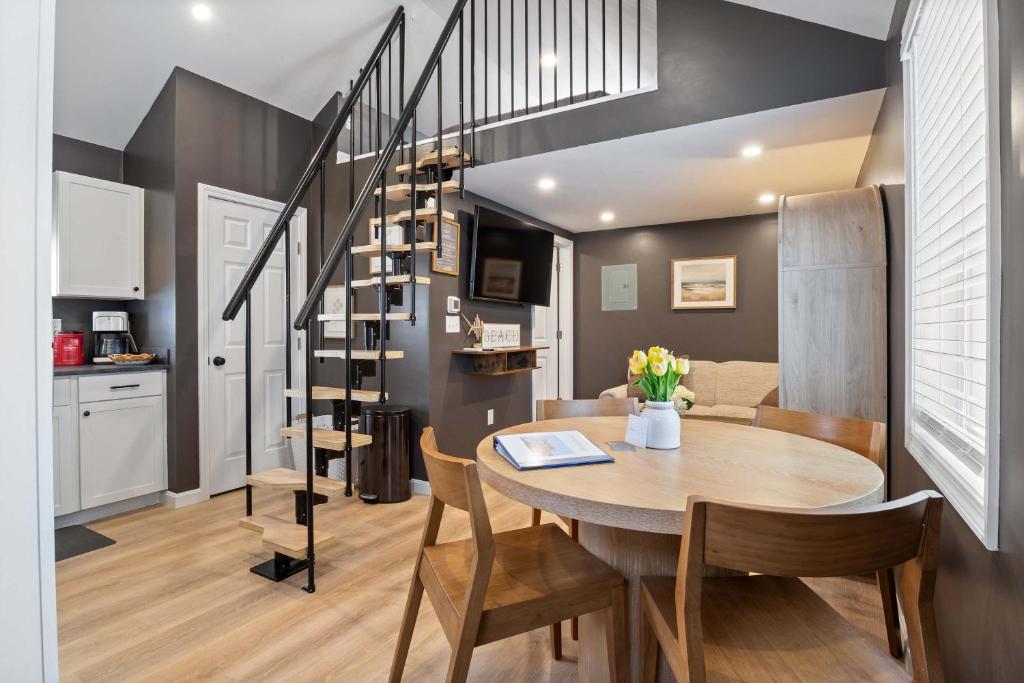 a dining room and kitchen with a table and a staircase at Coral Cottage - Tiny Home at Hampton Beach in Hampton