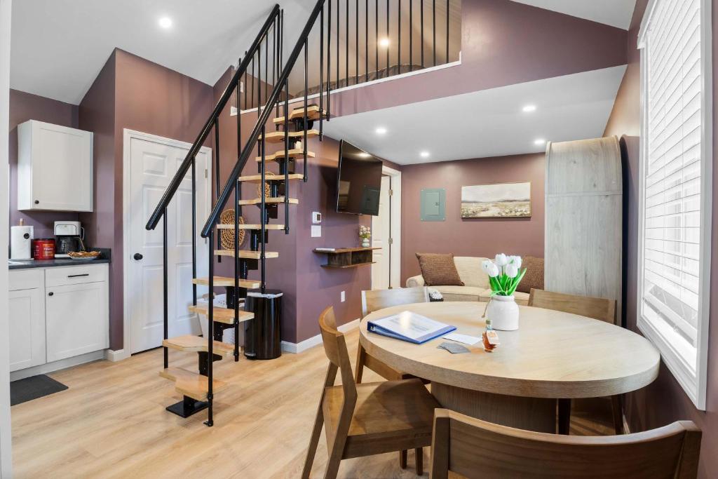 a dining room and kitchen with a table and a spiral staircase at Coastal Breeze Cottage - Tiny Home at Hampton Beach in Hampton