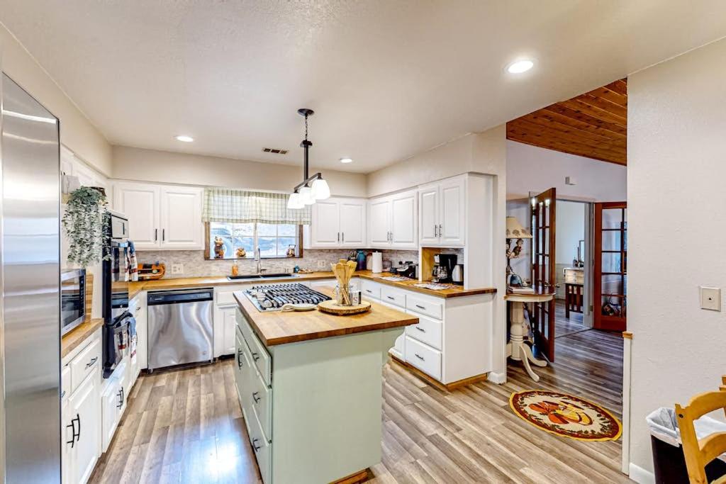 a large kitchen with white cabinets and wooden floors at Creekside Cabin in Crestline