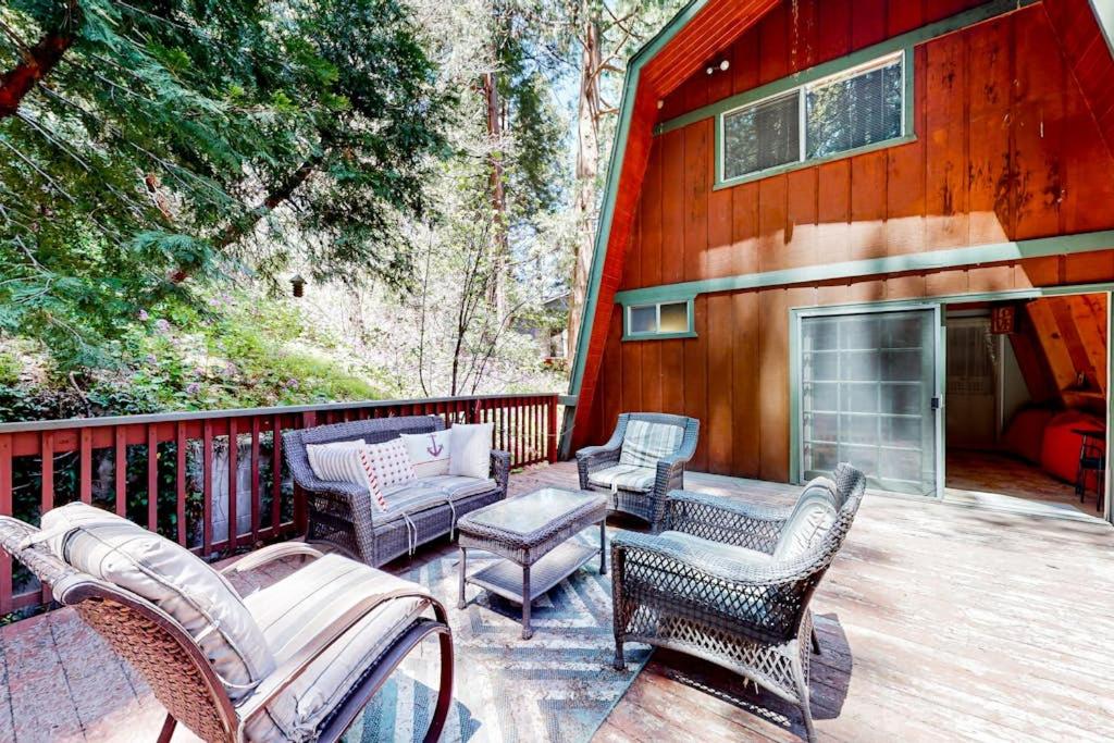 a deck with chairs and a fireplace on a house at Hidden Wonder in Crestline