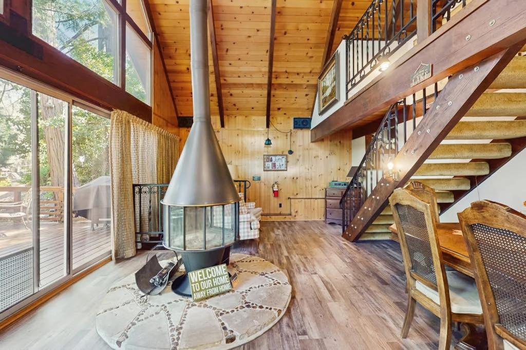 a living room with a fireplace and wooden stairs at Retro Cabin in Lake Arrowhead