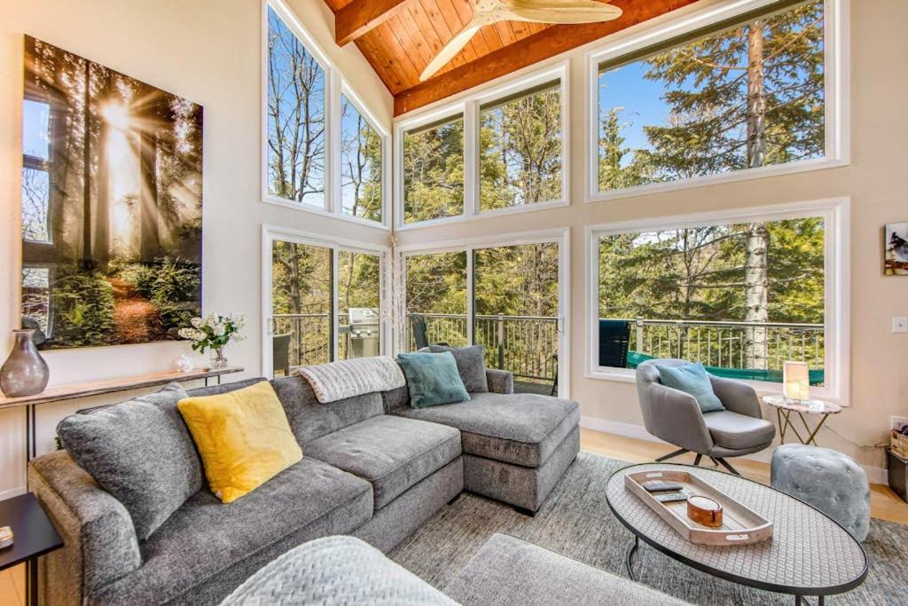 a living room with a couch and chairs and large windows at Timber Top Retreat in Lake Arrowhead