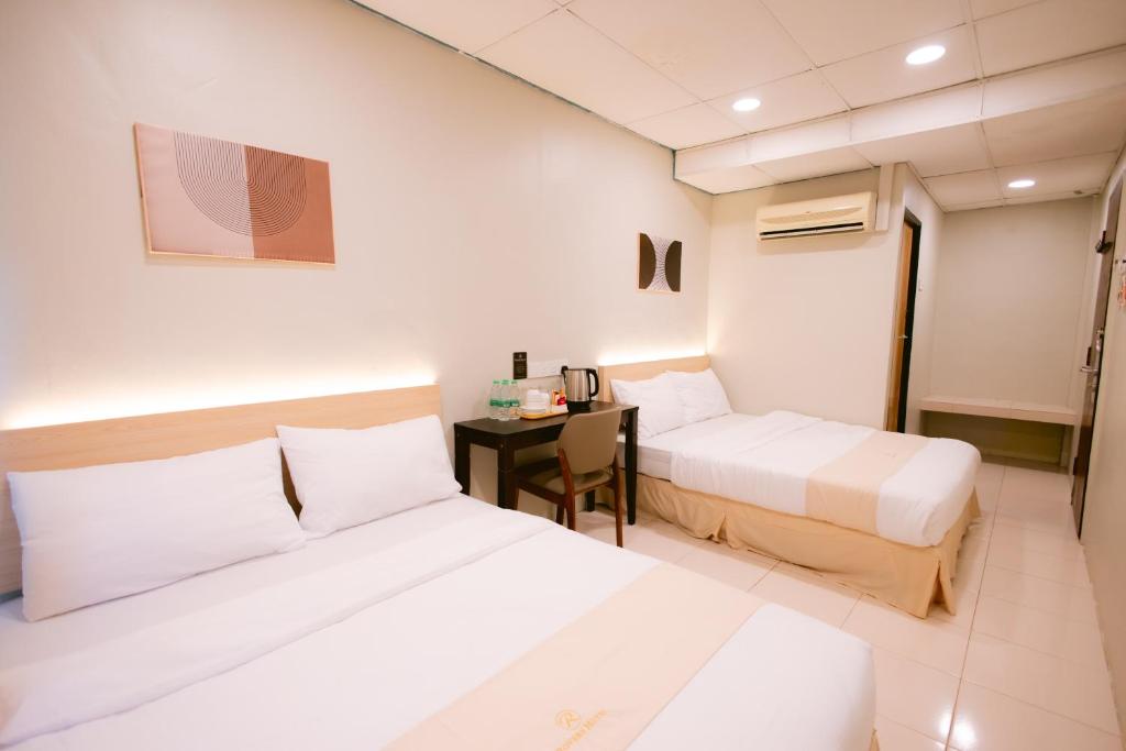 a hotel room with two beds and a desk at Rovers Hotel Kubang Kerian in Kota Bharu