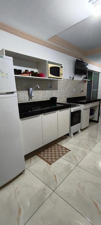 una cucina con mobili bianchi, lavello e frigorifero di AP BAIRRO de FÁTIMA Familiar a Itabuna