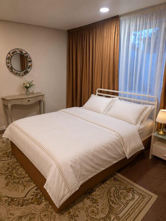 a bedroom with a large white bed with a window at Баракат in Chon-Sary-Oy