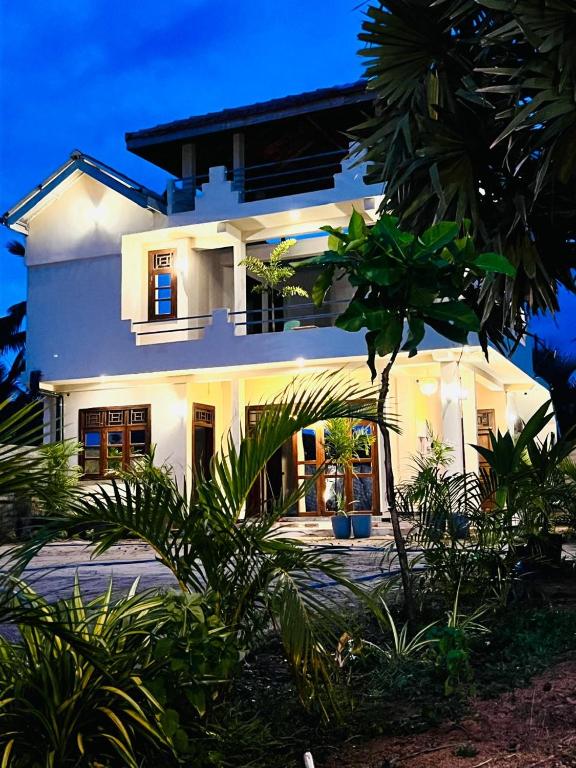 a white house with a lot of plants in front of it at Luna Mara in Arugam Bay