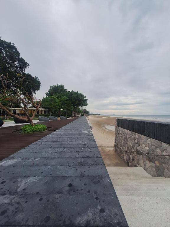 a walkway leading to the beach with a stone wall at บ้านแสนสุขคอนโดติดทะเล By Nichahome in Hua Hin