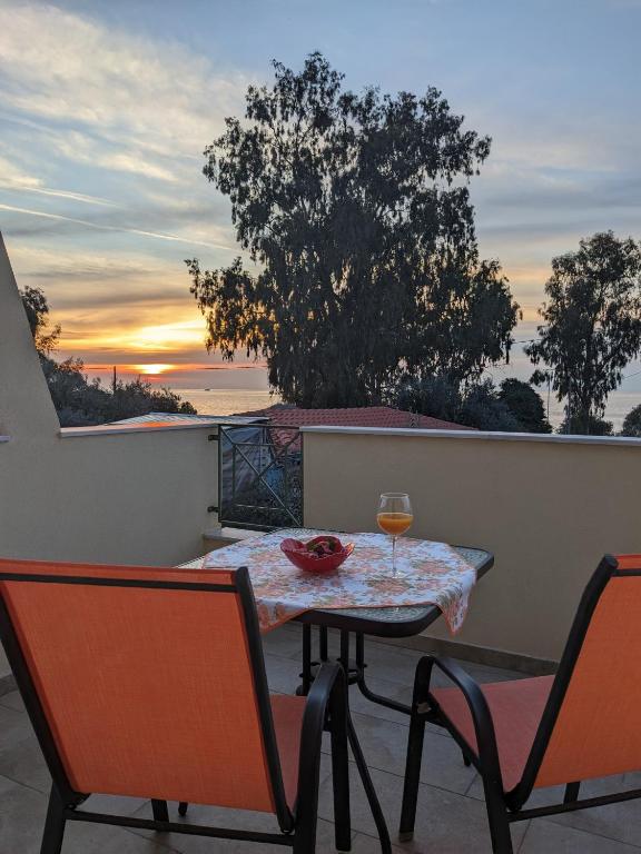 a table and chairs on a balcony with a glass of wine at Harmony Sunset in Skala Sotiros