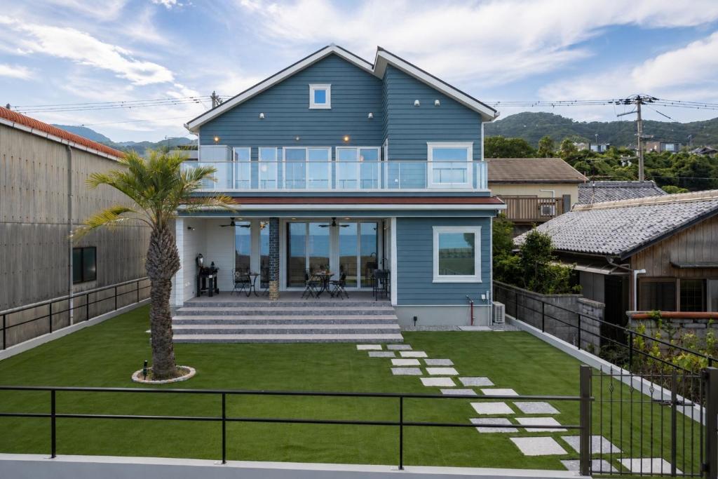 a blue house with a palm tree in the yard at Verda Rico in Awaji
