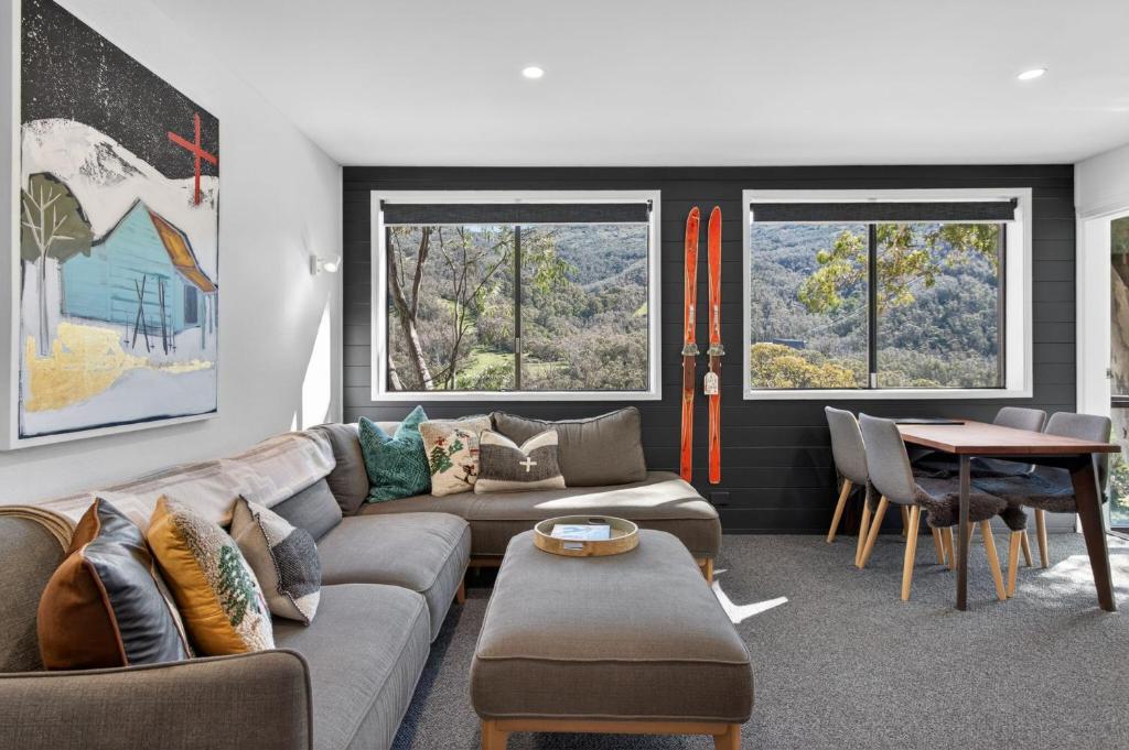 a living room with a couch and a table and two windows at Tyrola 11 in Thredbo