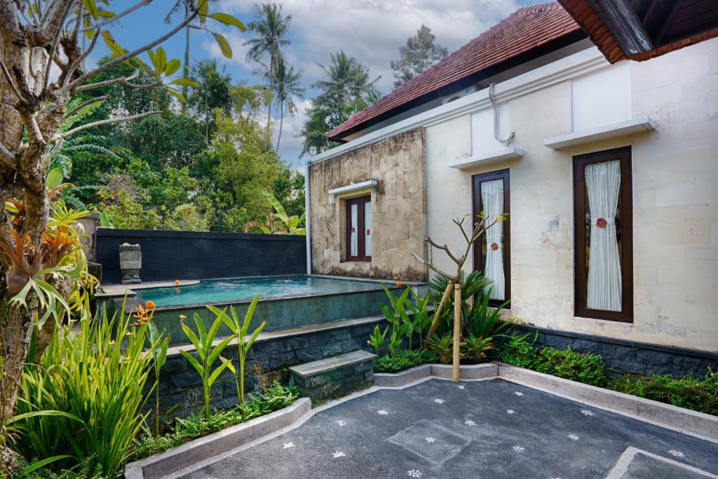 a house with a swimming pool in a garden at Kubu Kapas Bali in Ubud