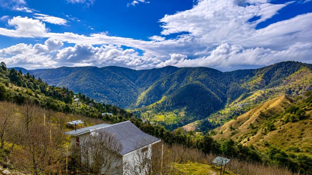 a house on a hill with mountains in the background at Orchard Valley Resort in Mai Jūbar