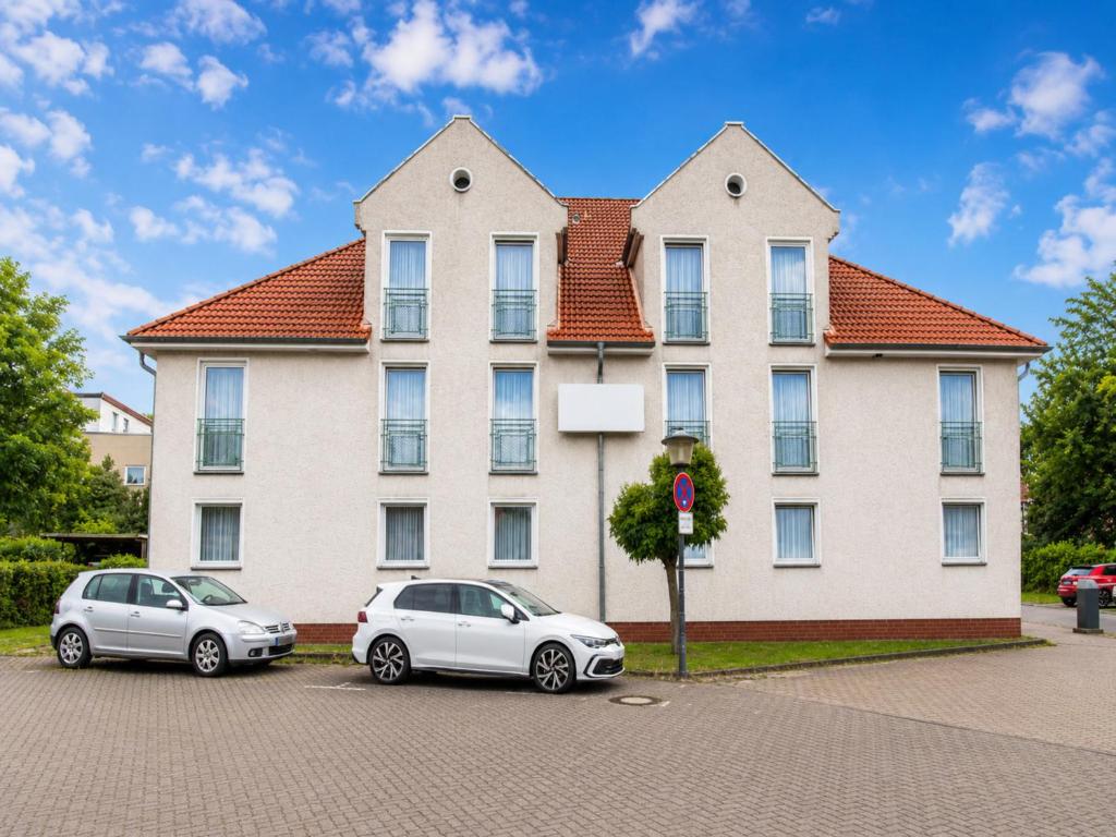two cars parked in front of a large building at Wolfsburg Fallersleben Hotel by Belvilla in Wolfsburg