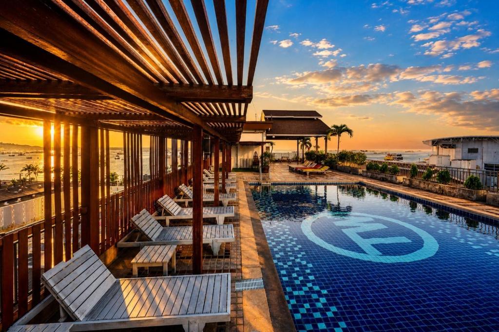 a hotel swimming pool with lounge chairs and the ocean at Baywalk Residence Pattaya in Pattaya