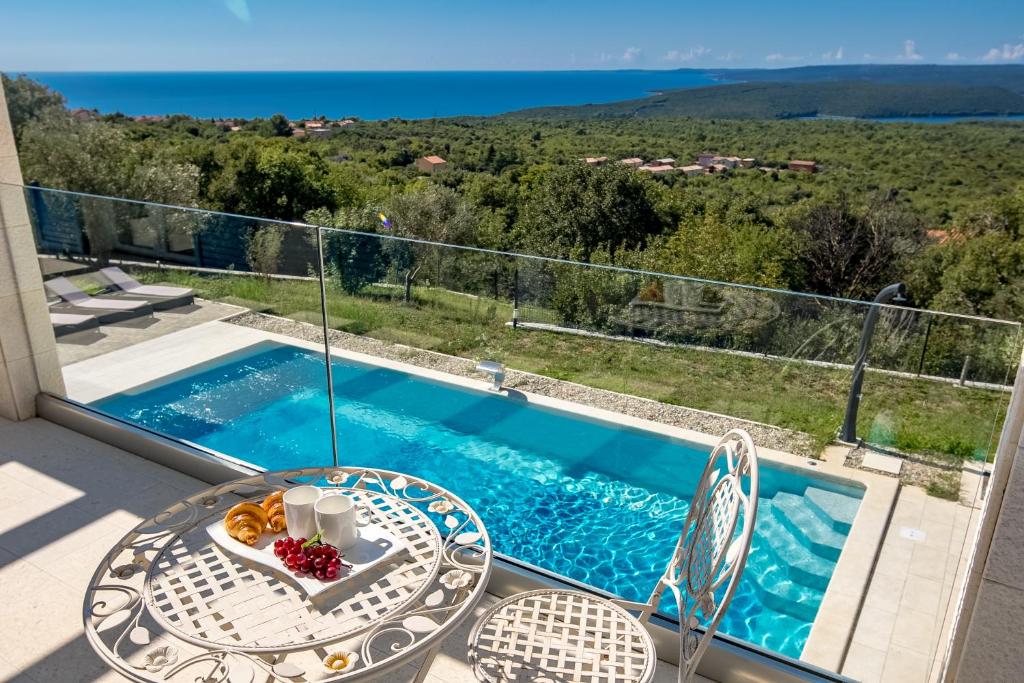 a balcony with a table and chairs and a swimming pool at Villa Luka with Private Pool & Sea View in Labin