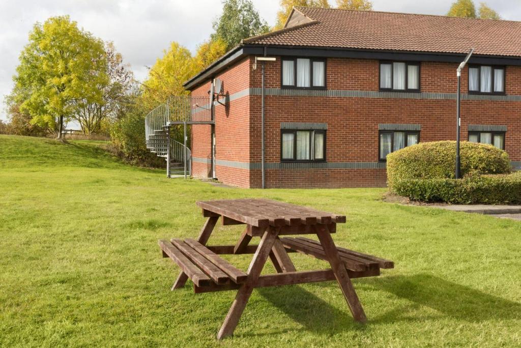 a wooden picnic table in front of a building at Days Inn Hotel Sheffield South in Harthill