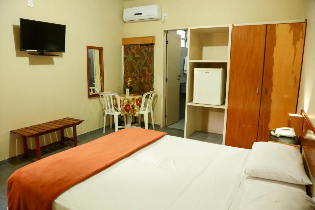 a bedroom with a bed and a table and a television at Pousada Abais in Aracaju