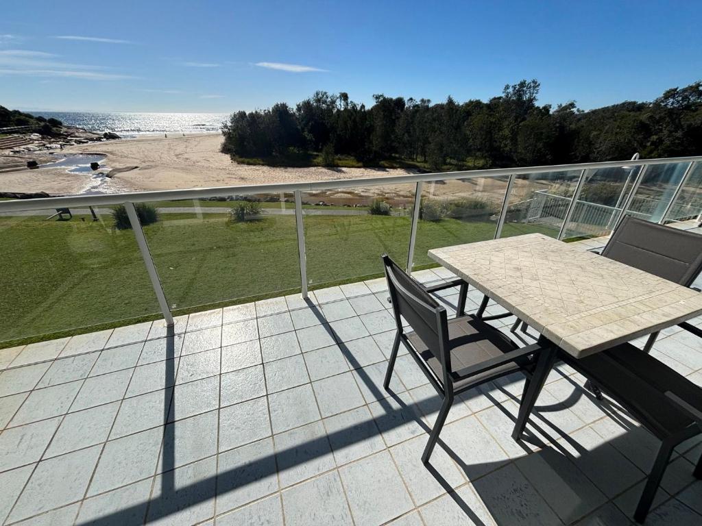 a table and chairs on a balcony with a view of the beach at Ocean Shores Apartment 15 - Bring your own linen. in South West Rocks