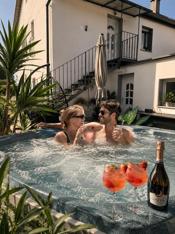 a man and a woman in a hot tub with wine glasses at Csobogó Suites Apartman in Keszthely