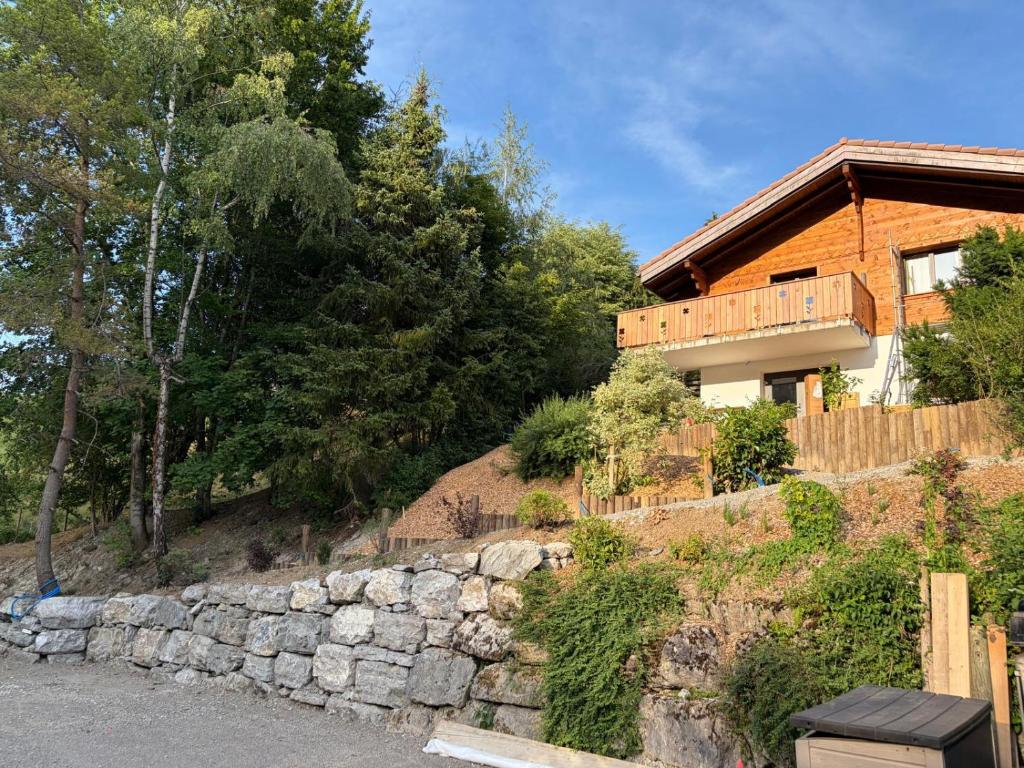 a house on a hill with a stone wall at Chalet du Lac in Charmey