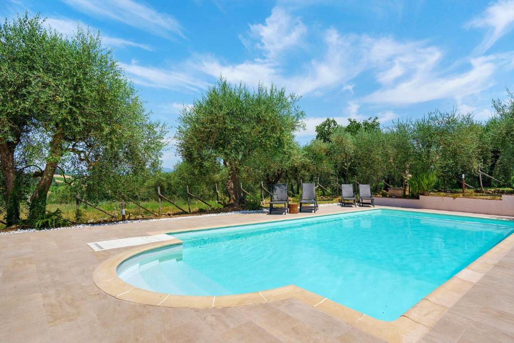 a swimming pool in a yard with chairs and trees at Agriturismo Santa Luce in Foiano della Chiana