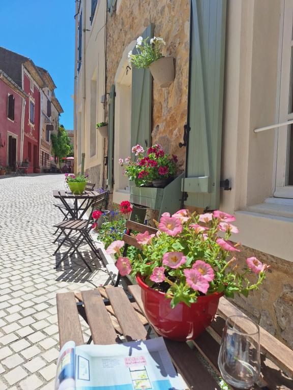 a wooden bench with flowers on a street at La Retraite in Assignan